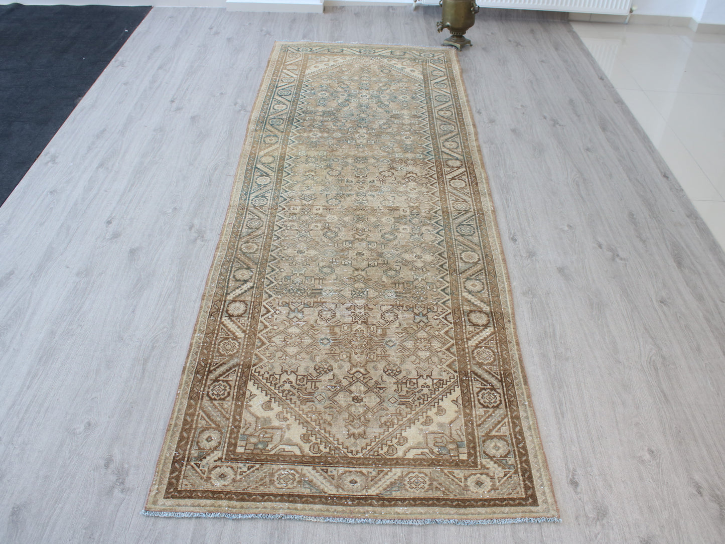 A long rectangular area rug with an intricate traditional floral pattern, laid out on a light gray wood-plank floor.