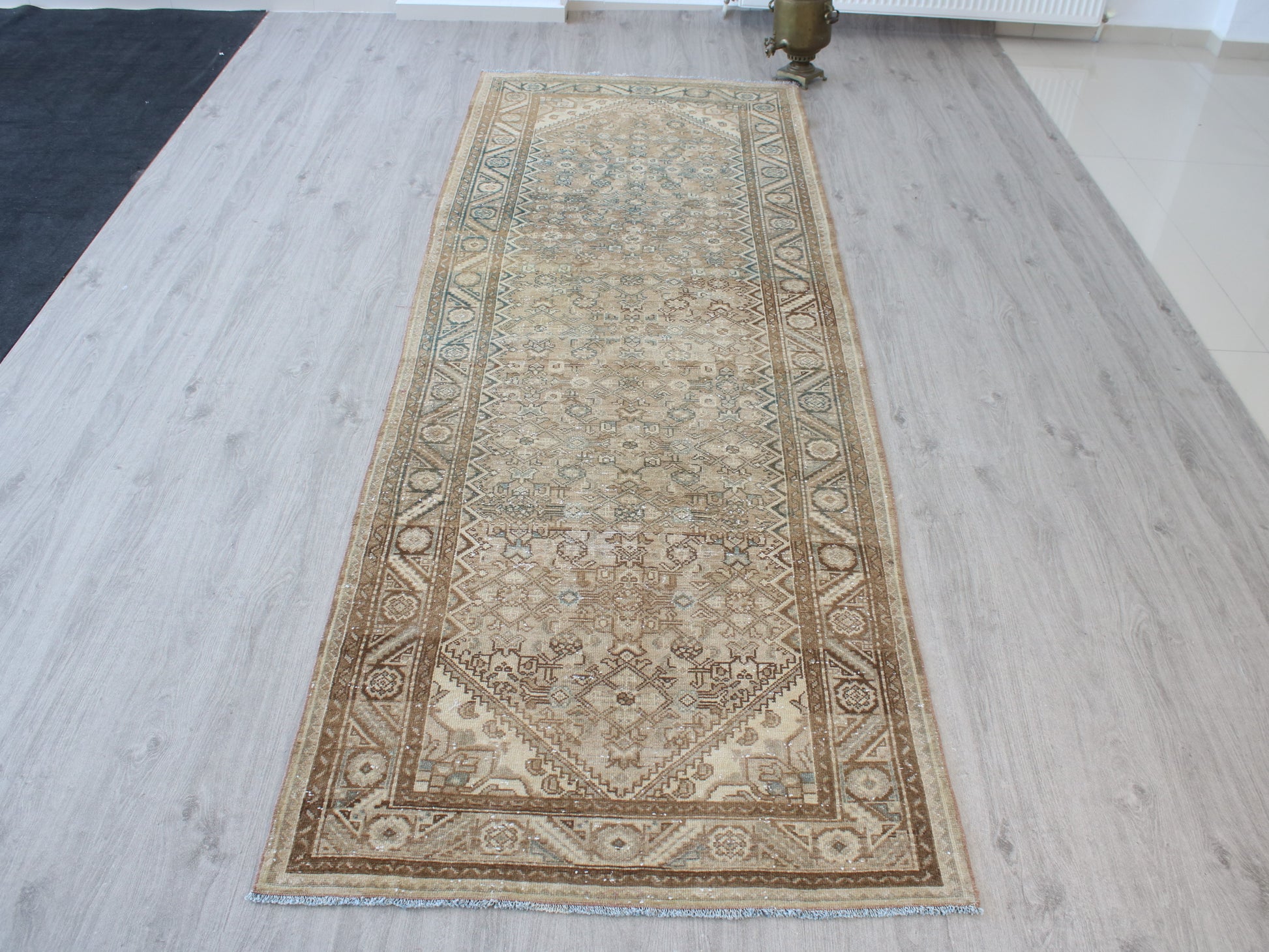 A long rectangular area rug with an intricate traditional floral pattern, laid out on a light gray wood-plank floor.