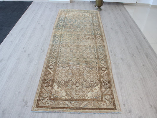 A long rectangular area rug with an intricate traditional floral pattern, laid out on a light gray wood-plank floor.